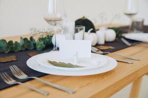 Thanksgiving table setting, tableware and decorations. Blank white postcard on table mockup. photo