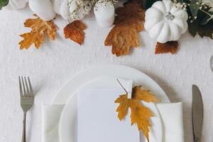 Thanksgiving table setting, tableware and decorations. Blank white postcard on table mockup, top view photo