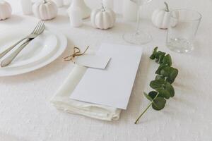 Thanksgiving table setting, tableware and decorations. Blank white postcard on table mockup. photo