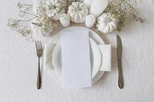 Thanksgiving table setting, tableware and decorations. Blank white postcard on table mockup, top view photo