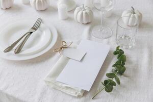 Thanksgiving table setting, tableware and decorations. Blank white postcard on table mockup. photo