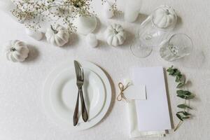 Thanksgiving table setting, tableware and decorations. Blank white postcard on table mockup, top view photo