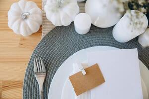 Thanksgiving table setting, tableware and decorations. Blank white postcard on table mockup. photo
