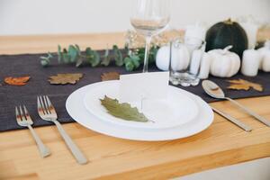 Thanksgiving table setting, tableware and decorations. Blank white postcard on table mockup. photo