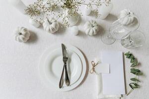 Thanksgiving table setting, tableware and decorations. Blank white postcard on table mockup, top view photo