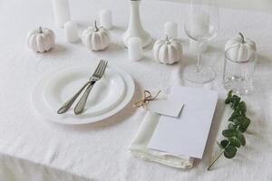 Thanksgiving table setting, tableware and decorations. Blank white postcard on table mockup. photo