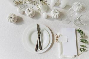 Thanksgiving table setting, tableware and decorations. Blank white postcard on table mockup, top view photo