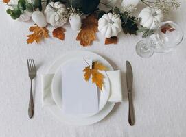 Thanksgiving table setting, tableware and decorations. Blank white postcard on table mockup, top view photo