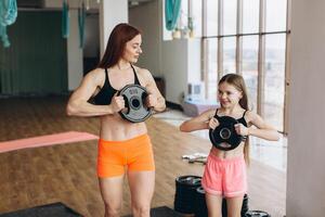 Mom and Daughter are doing exercises. Family in a gym. Little girl with strong mother are training photo