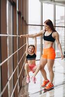 The daughter holds on to the mother's strong hand in the gym during training photo