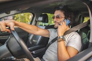 Man with curly hair driving a car, smoking a cigarette and using phone photo
