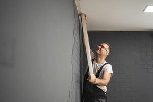 Man sticks protective tape on the wall before painting photo