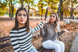 Two women are sitting on a bench and one does not want to listen to the other anymore photo