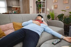 Man with wireless headphones fell asleep while reading a book at home photo