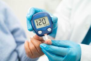 Doctor use digital glucose monitor measure and test stripe for check diabetes from finger blood sugar level. photo