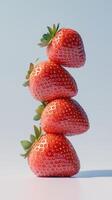 A stack of strawberry fruit balancing on top with pink solid background photo