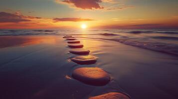Stepping grey stones with texture forwarding in beach sand and ocean water with sunset sky photo