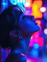 Young woman in profile illuminated by colorful neon lights at night photo