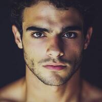 Handsome young man with striking features in a dimly lit setting photo