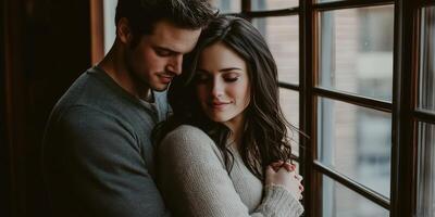 A couple embraces by the window in a cozy indoor setting photo
