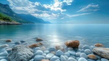Tranquil sea with white pebbles on the beach and mountains in the distance photo