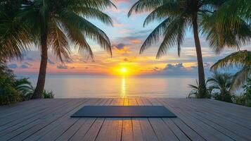 Yoga mat lying on wooden deck overlooking tropical ocean sunset with palm trees photo