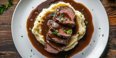 Indulge in a succulent roast beef dish, generously topped with a rich and flavorful demi glace gravy, all served alongside creamy mashed potatoes, creating a hearty and satisfying meal experience photo
