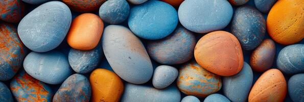 An assortment of smooth pebbles in vibrant blue, orange, and gray colors creating a beautiful and colorful display photo