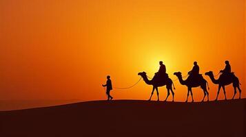 Silhouette of Camel Riders Against an Orange Hued Sky on a Desert Dunes Under Dramatic Sunset photo