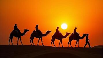 Silhouette of Camel Riders Against an Orange Hued Sky on a Desert Dunes Under Dramatic Sunset photo