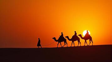 Silhouette of Camel Riders Against an Orange Hued Sky on a Desert Dunes Under Dramatic Sunset photo
