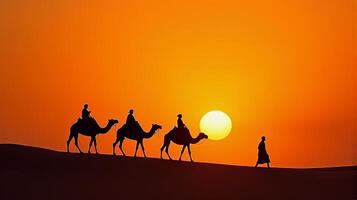 Silhouette of Camel Riders Against an Orange Hued Sky on a Desert Dunes Under Dramatic Sunset photo