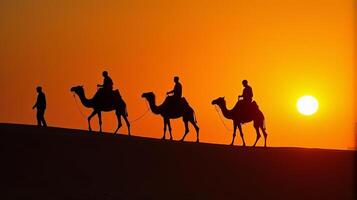 Silhouette of Camel Riders Against an Orange Hued Sky on a Desert Dunes Under Dramatic Sunset photo