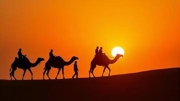 Silhouette of Camel Riders Against an Orange Hued Sky on a Desert Dunes Under Dramatic Sunset photo