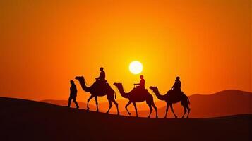 Silhouette of Camel Riders Against an Orange Hued Sky on a Desert Dunes Under Dramatic Sunset photo