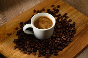 Arrangement of coffee cup and roasted coffee beans on rustic wooden background. photo
