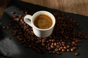 A composition with a cup of coffee and coffee beans scattered on the table photo