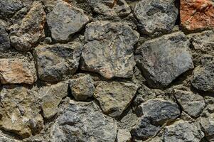 Stone wall texture background - grey stone siding with different sized stones photo