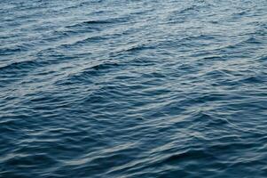 Transparent blue clear water surface texture with ripples, splashes and bubbles photo