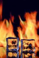 Conceptual photograph of an ice cube engulfed in flames, symbolizing the contrast between fire and ice. photo