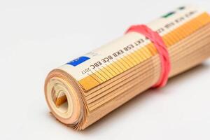 Roll of Euro bank notes, isolated on white, with a reflection underneath photo
