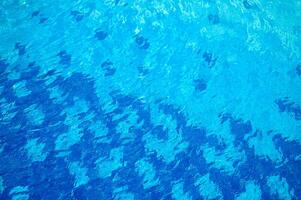 Blue water texture with light reflection. Water surface with rings and ripples, splashes and bubbles photo