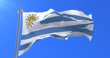 Flag of Uruguay waving at wind in slow with blue sky, loop video