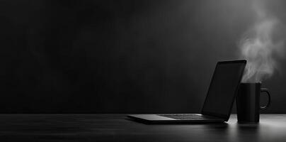 Laptop and coffee cup on black table in office. Workplace concept photo