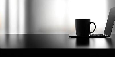 Laptop and coffee cup on black table in office. Workplace concept photo