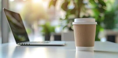 Blurred background of a modern home office interior with a laptop computer and a coffee cup on a white table, with copy space for text in the blurred window view. Business work from home concep photo