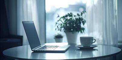 Blurred background of a modern home office interior with a laptop computer and a coffee cup on a white table, with copy space for text in the blurred window view. Business work from home concep photo