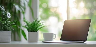 Blurred background of a modern home office interior with a laptop computer and a coffee cup on a white table, with copy space for text in the blurred window view. Business work from home concep photo