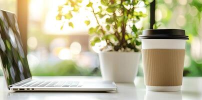 Blurred background of a modern home office interior with a laptop computer and a coffee cup on a white table, with copy space for text in the blurred window view. Business work from home concep photo