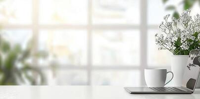 Blurred background of a modern home office interior with a laptop computer and a coffee cup on a white table, with copy space for text in the blurred window view. Business work from home concep photo